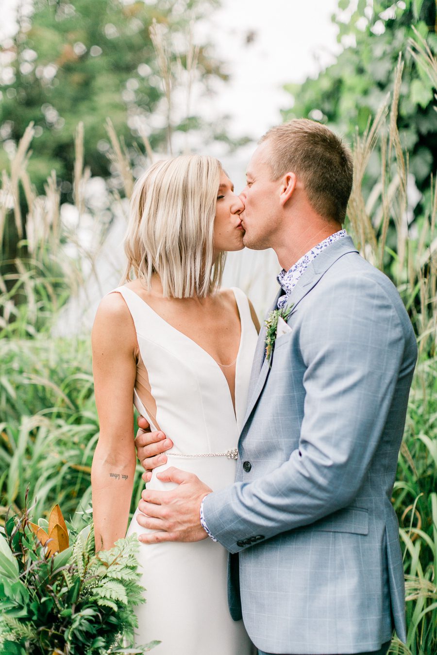 modern greenhouse wedding photos, carly mccray photography, lake geneva wedding photographer, madison wedding photographers, modern greenery wedding, modern wisconsin greenhouse wedding, modern greenery wedding, sleek wedding dress, greenery boutonnieres, black taper candles, green florals, modern greens